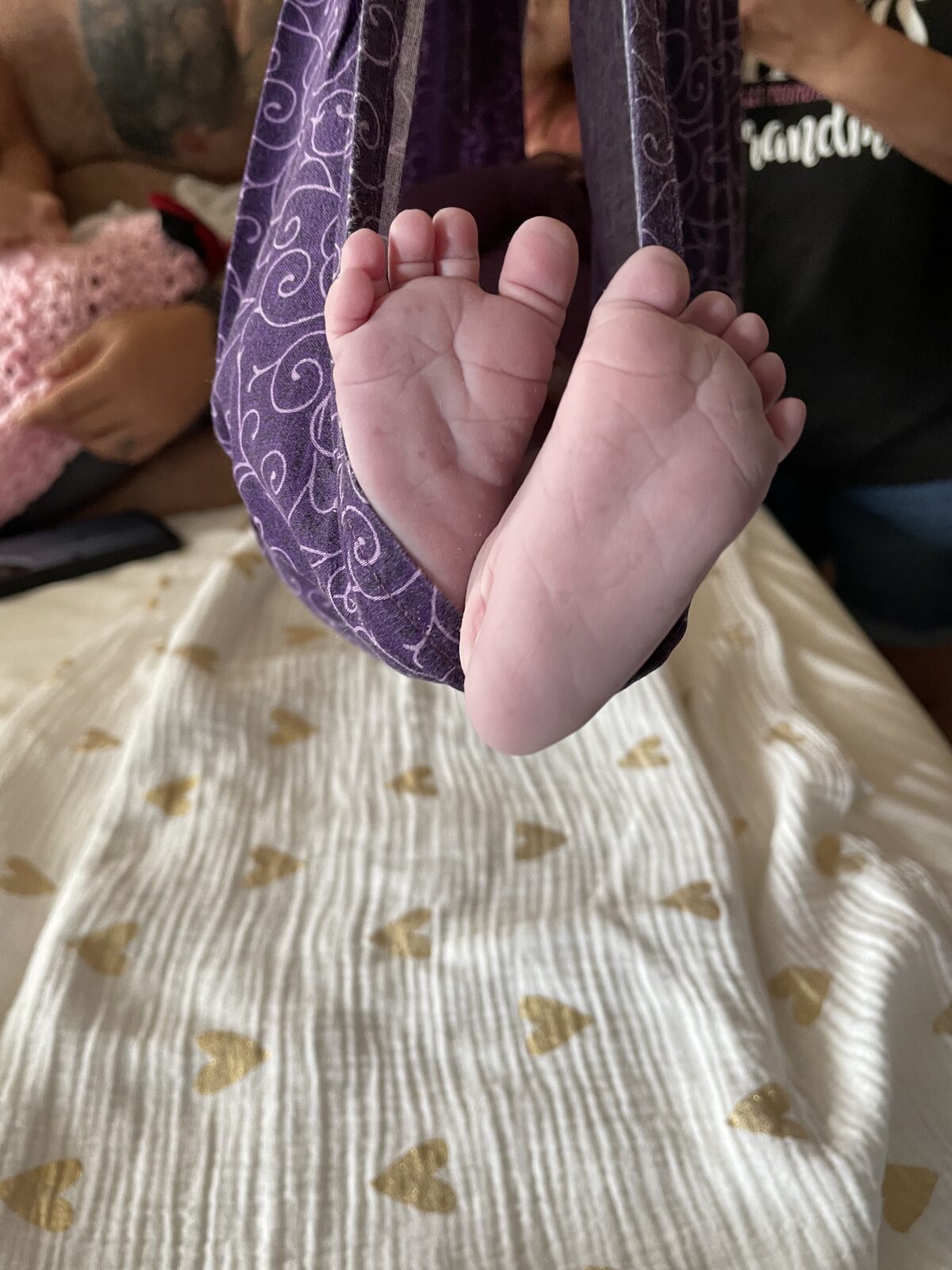 Newborn feet in a purple sling scale
