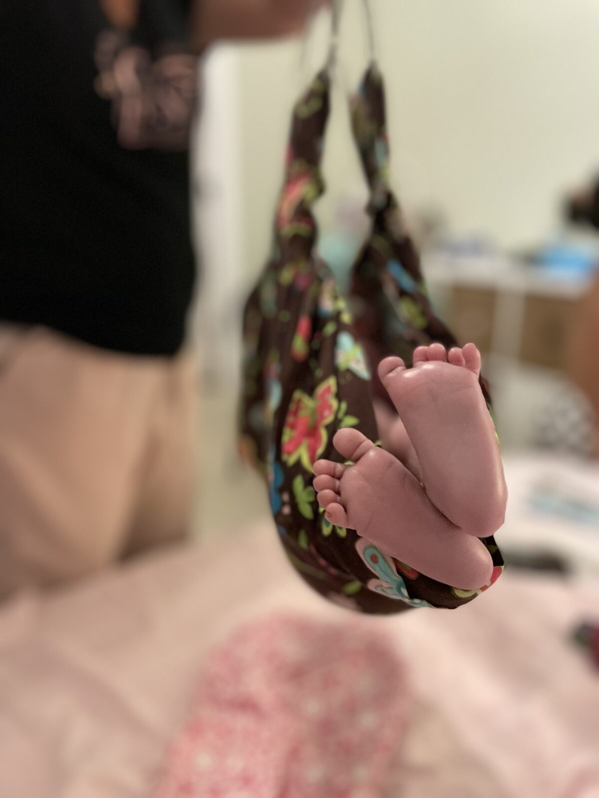 Newborn feet nestled in a floral sling