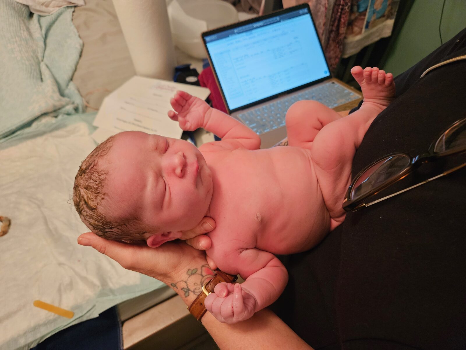 A newborn cradled in Rhonda's hands during the newborn exam