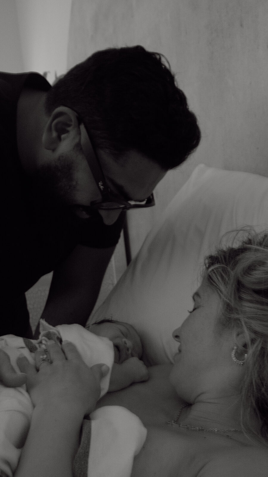 A father leaning in to meet his newborn moments after birth