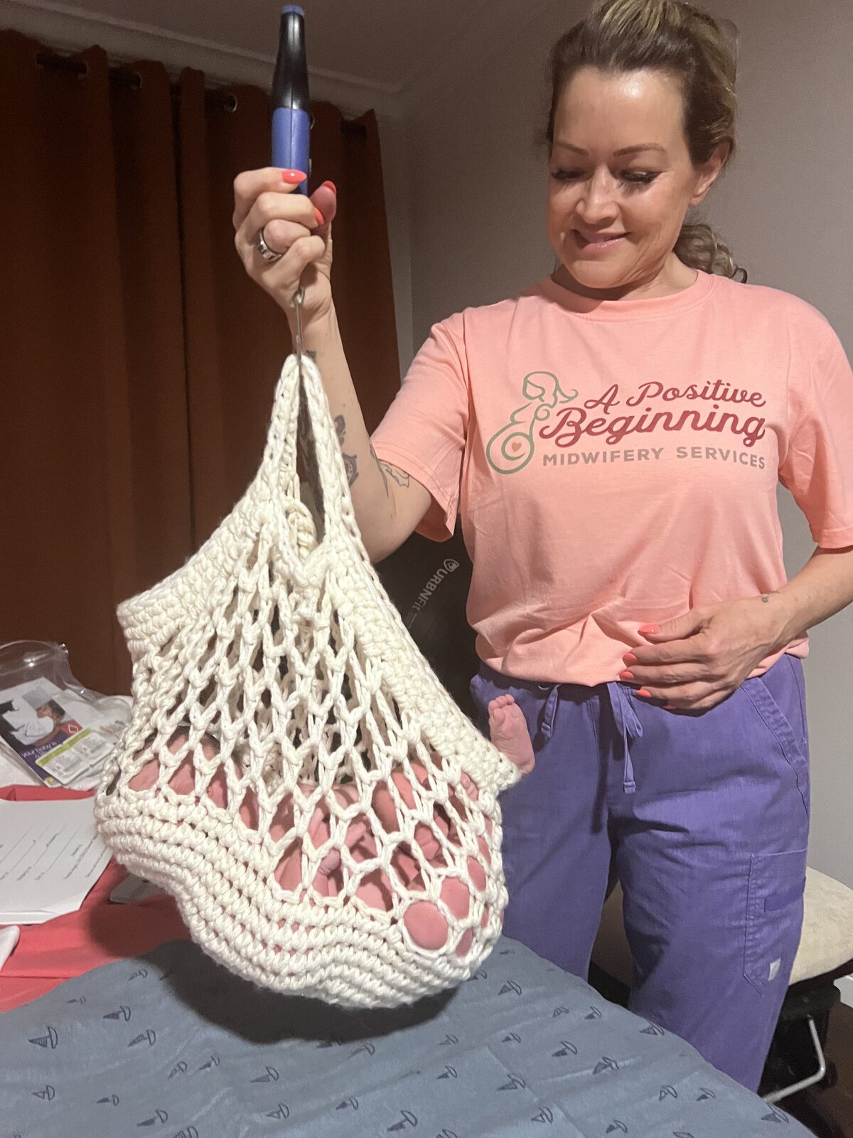 Rhonda Huggins weighing a newborn in her handmade crochet sling scale