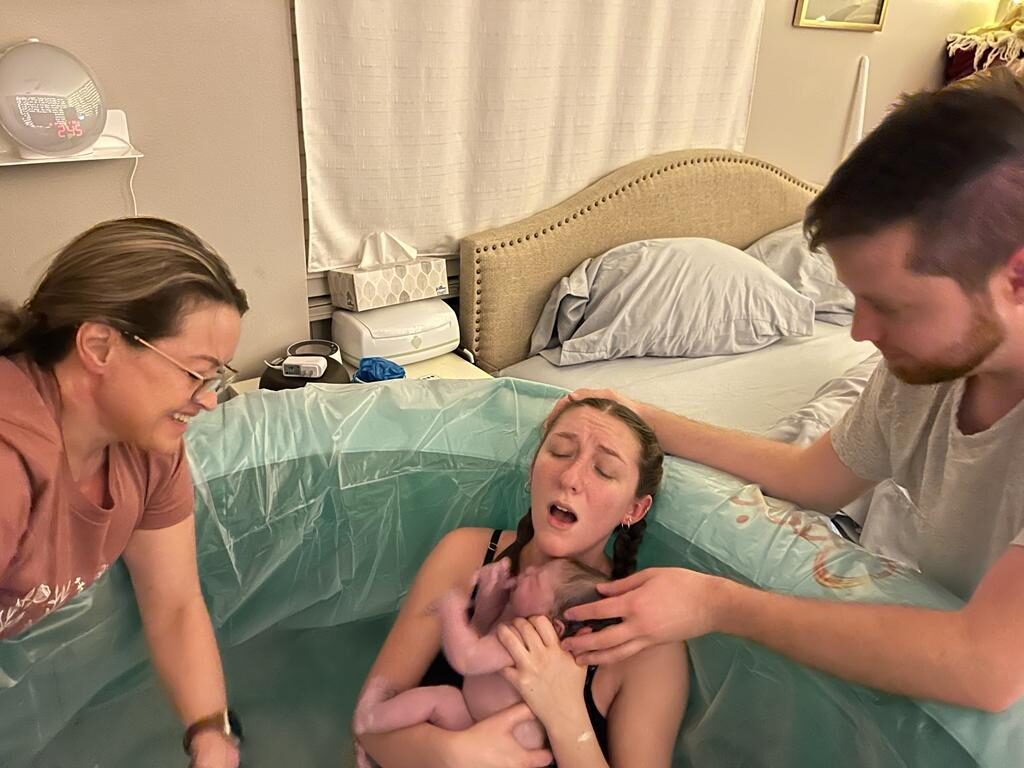 A mother meeting her just-born baby in the water