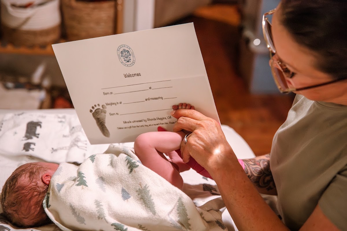 Rhonda Huggins taking a newborn's footprint on a Guardian Midwifery birth certificate